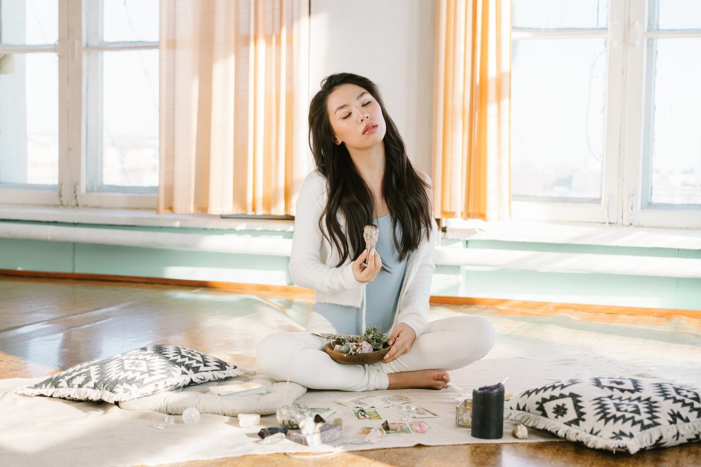 serene asian woman meditating with sage smudge stick